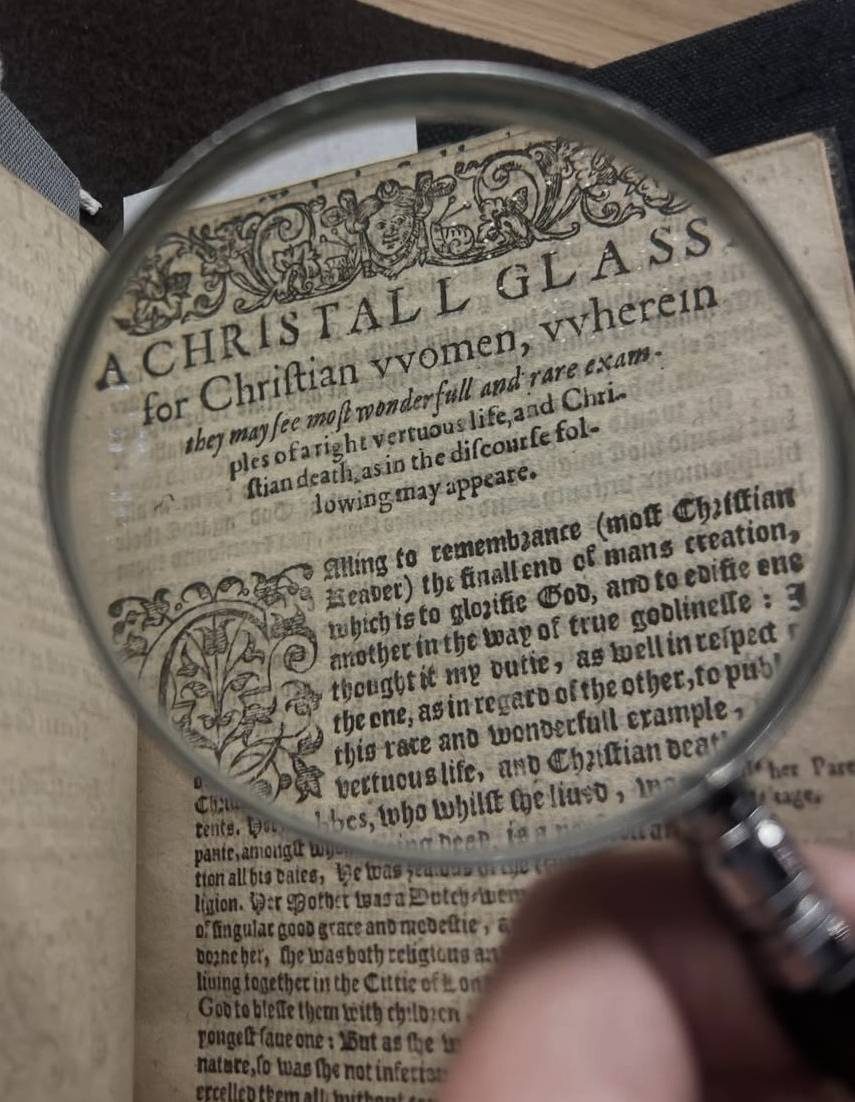 A printed heading of a page is magnified through a magnifying glass.