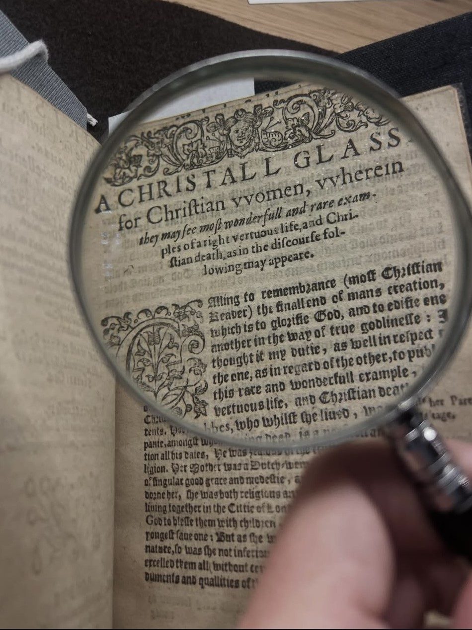 A printed heading of a page is magnified through a magnifying glass.