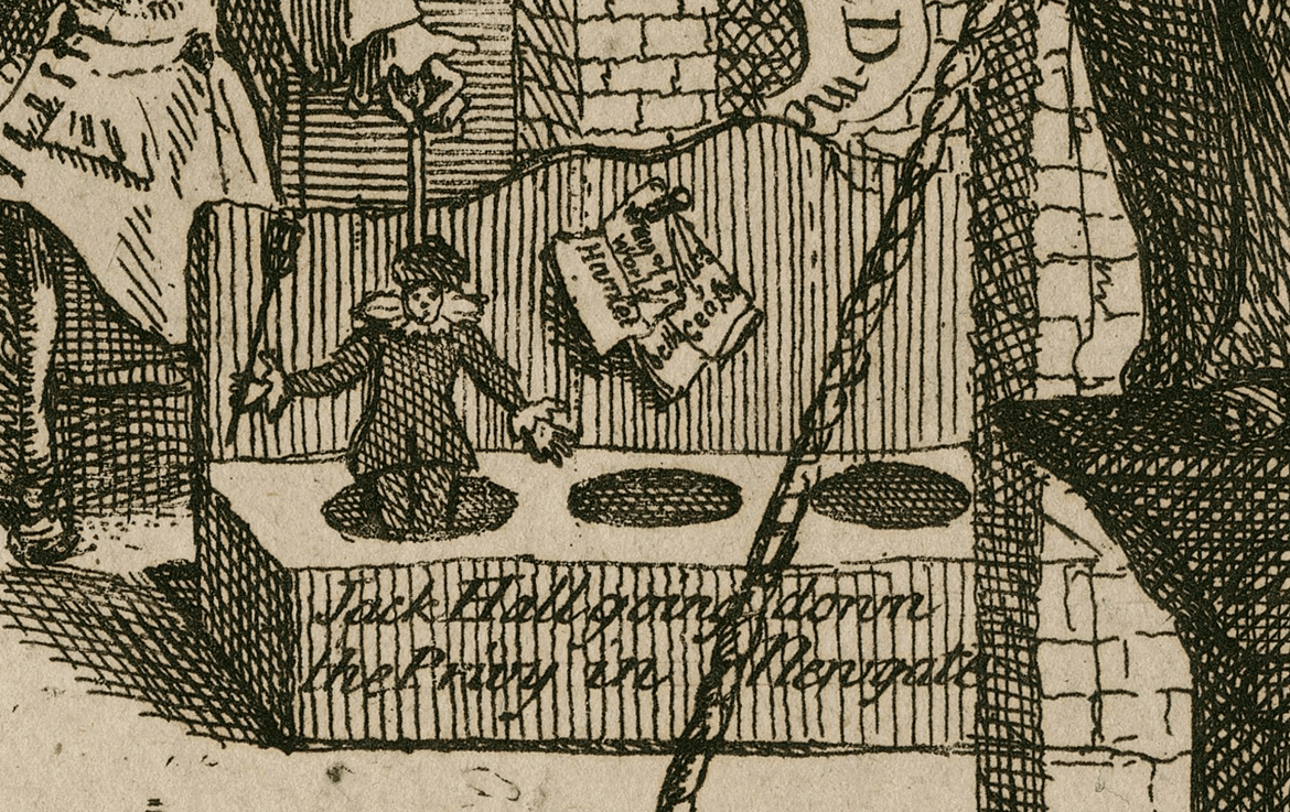 A puppet pops out of a crude toilet. Beside it, nailed to the wall to be used as toilet paper is Hamlet