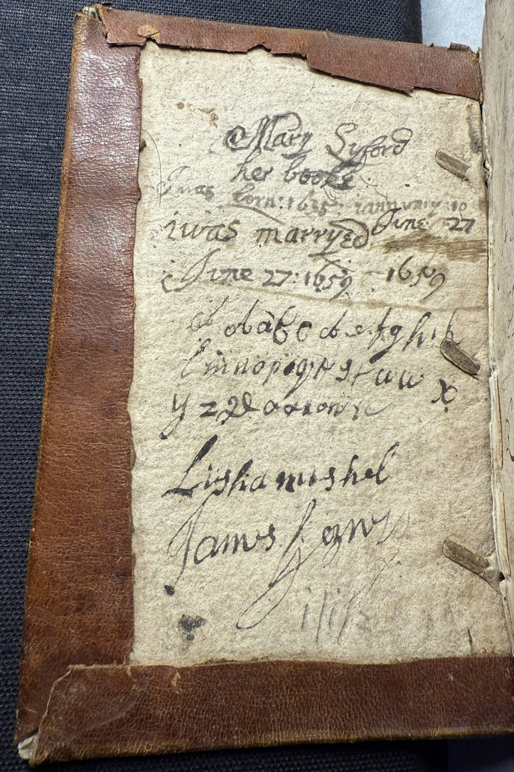 The board of a book showing the edges of the leather cover. The board is covered with manuscript text.
