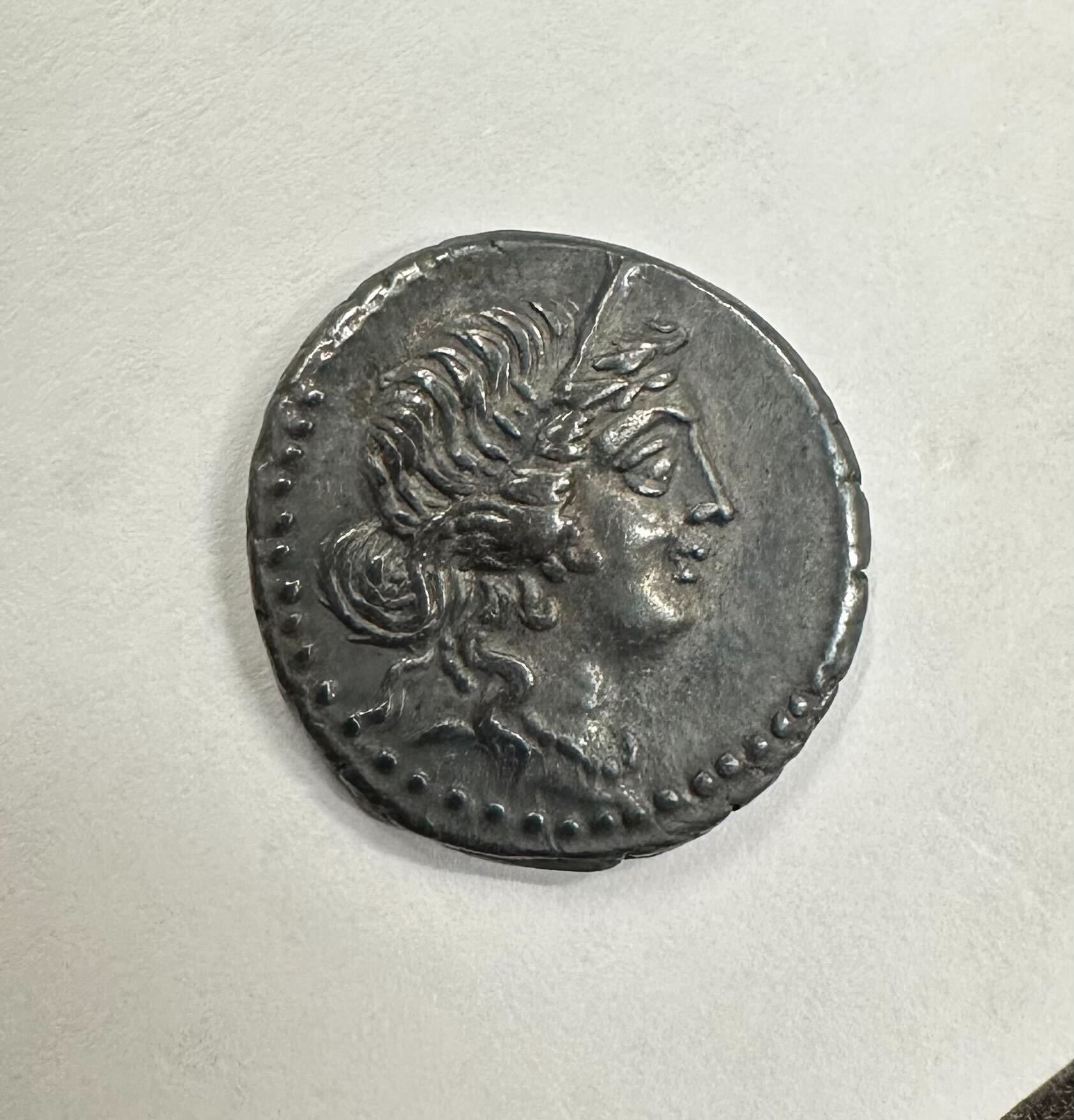 A silver coin showing a woman's head in profile.