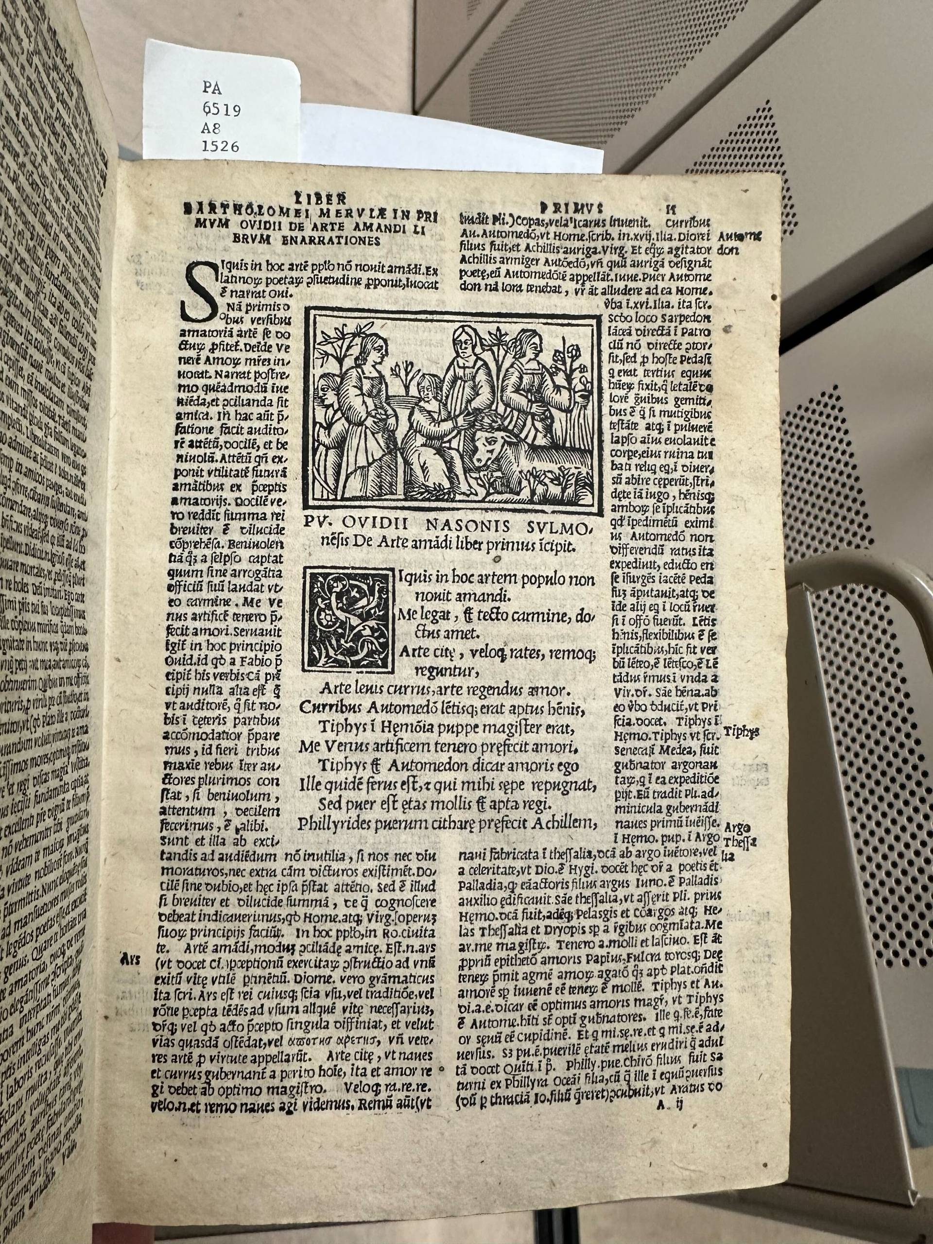 A printed page of a book showing two columns of text with a woodcut and poem inserted in-between them.