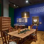 A large wooden table provides an interactive engagement space in the exhibition gallery