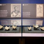 six books from the early modern period are shown open in an exhibition case