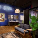 A couch and large plant create a small reading nook in the exhibition gallery