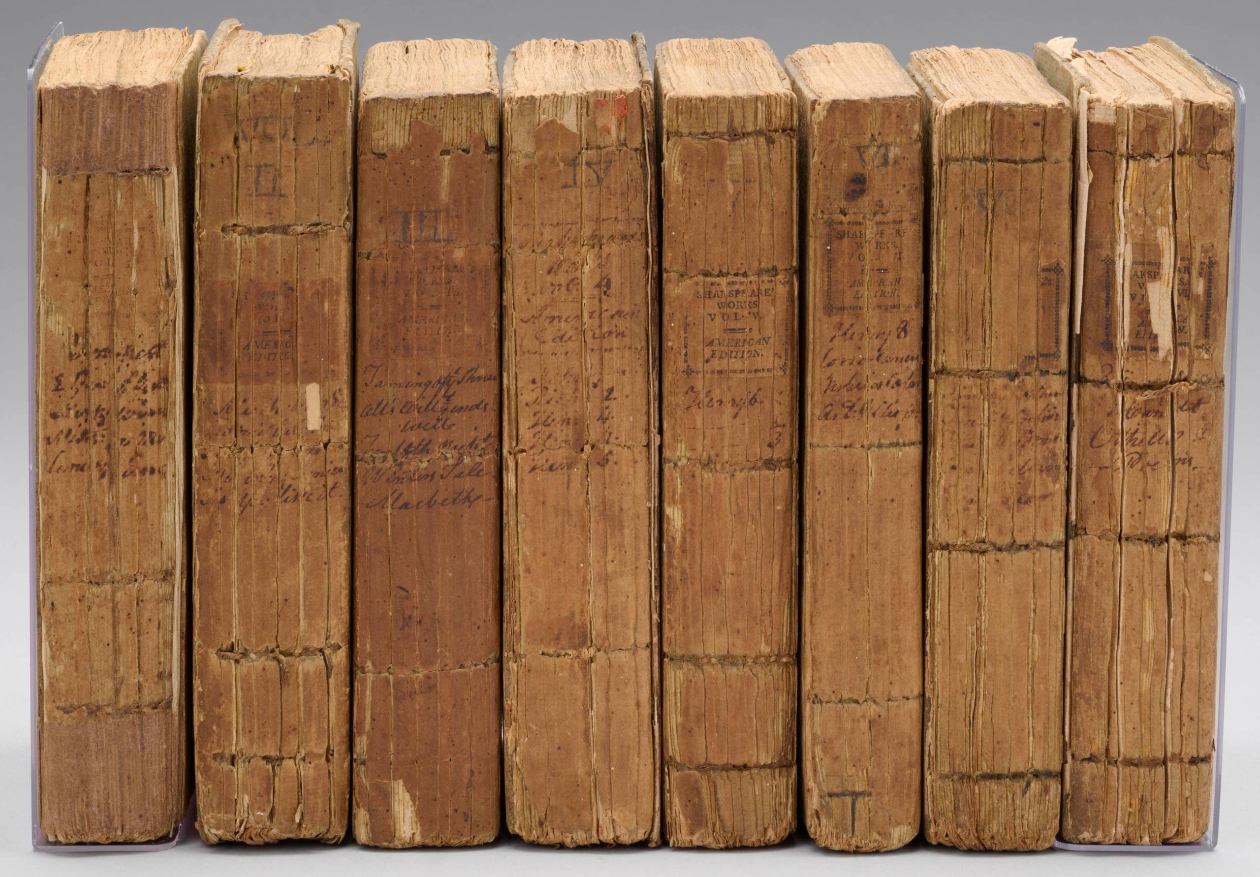 A set of eight upright books with cracked spines and handwritten titles facing outwards.