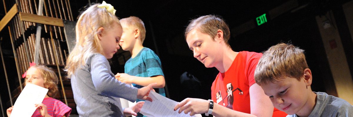 Group of children reading a piece of paper held by an adult