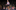 A girl standing on a theater stage talking out loud