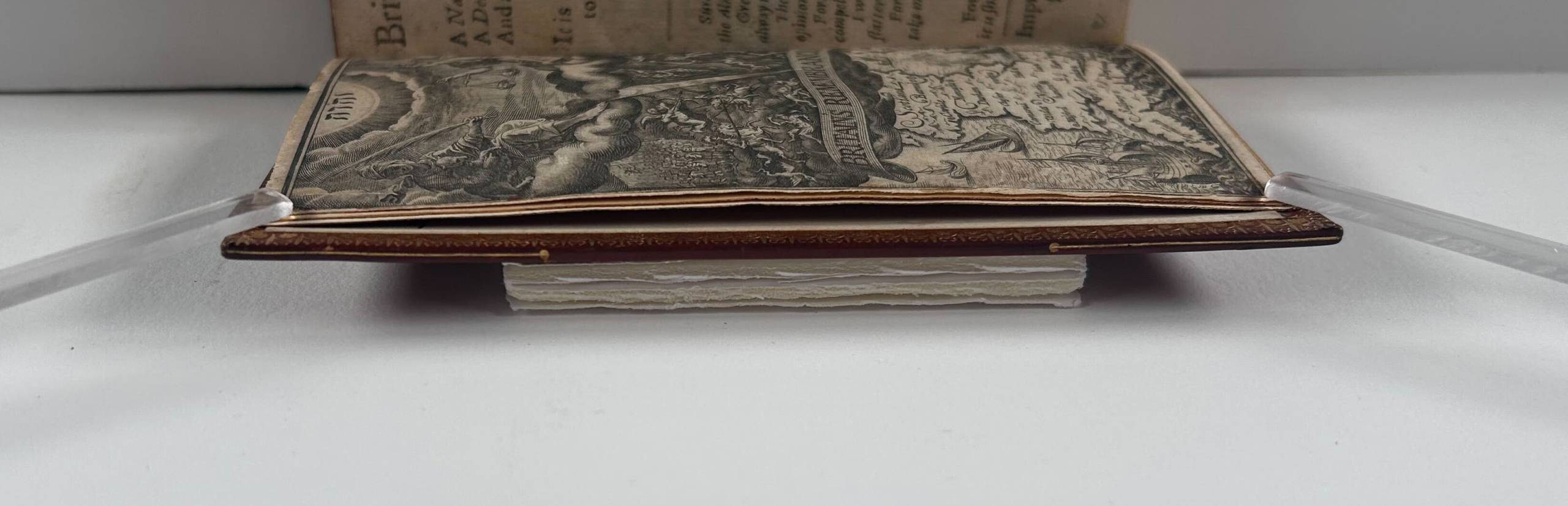 A book resting on a foam board, a clear stick holding down the first page