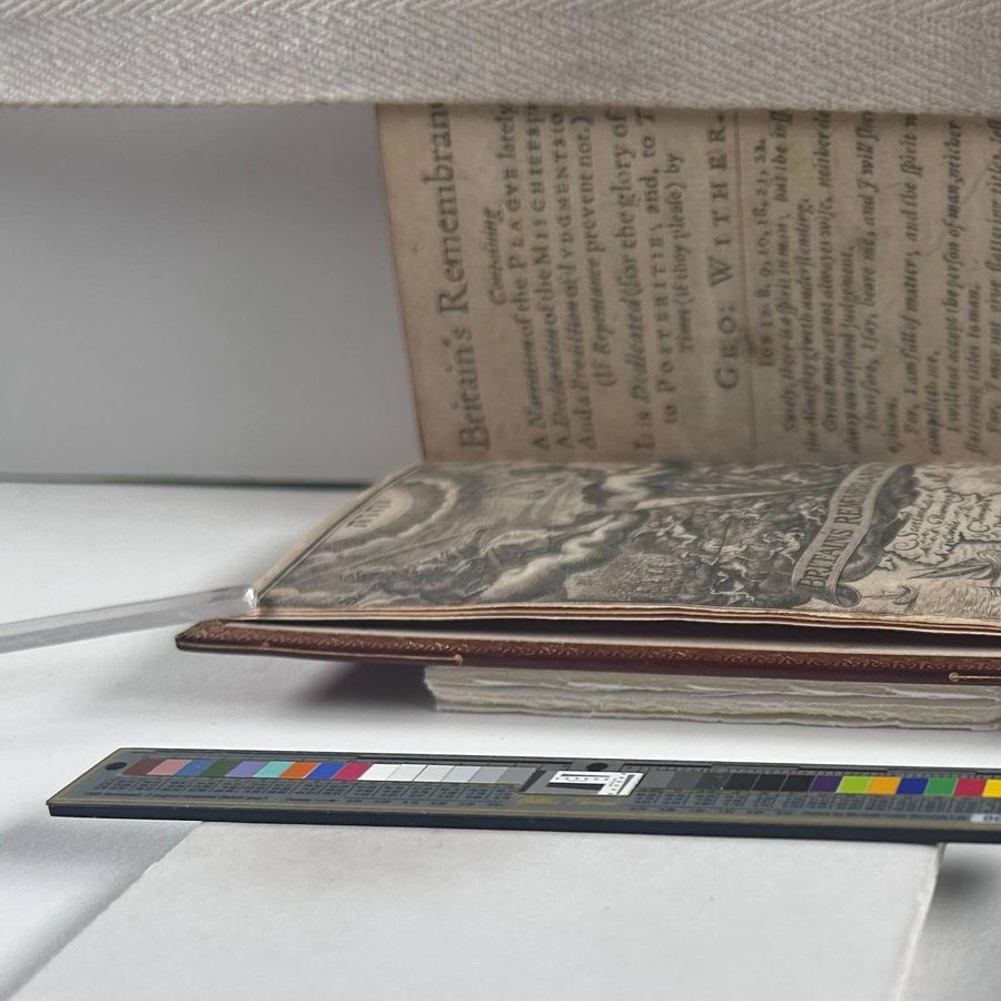 A book propped open, two clear plastic sticks holding the first page down