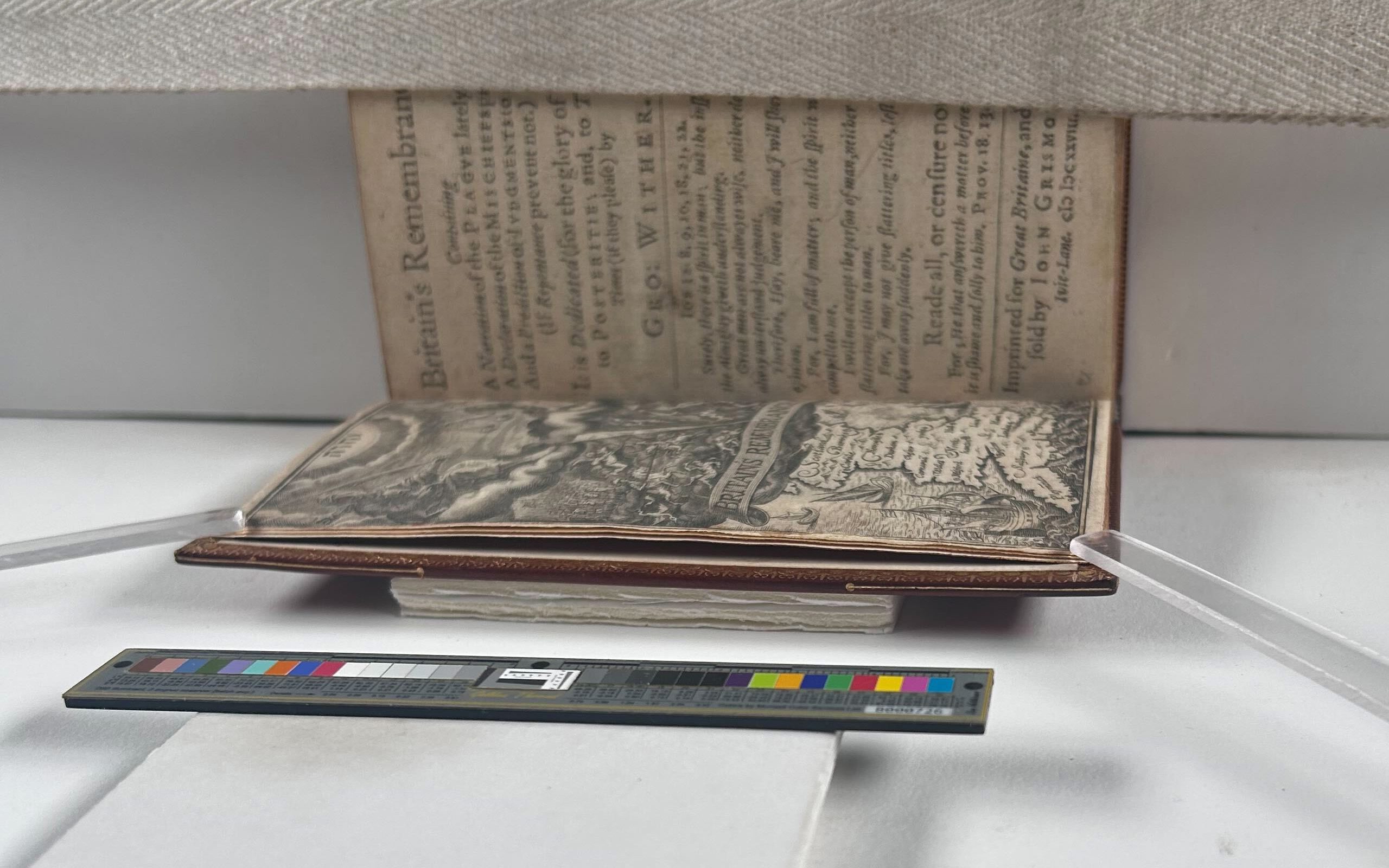 A book propped open, two clear plastic sticks holding the first page down